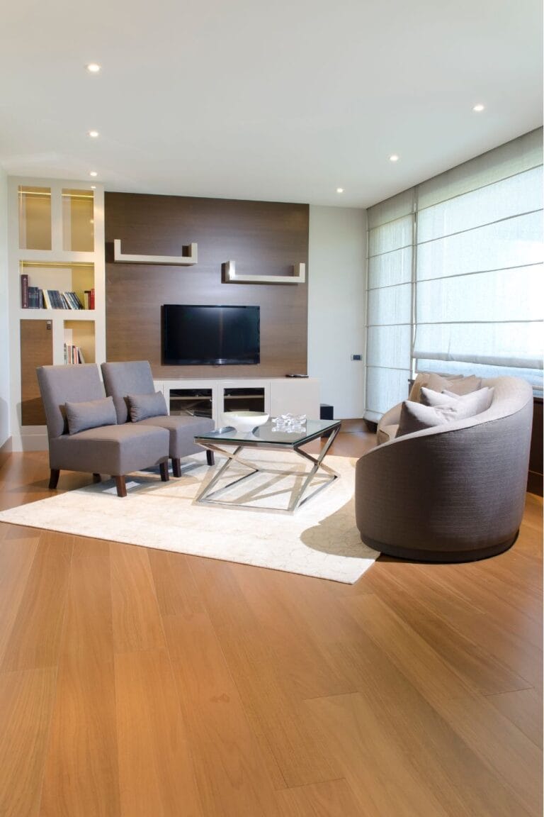 Modern living room with neutral furniture and a small area rug placed under a coffee table, showing an example of improper rug size for furniture grouping and layout.